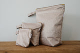 Picture shows set of 3 wet bags in the print beehaveLarge wet bag in print Beehave. Beautiful bronze background with a subtle bee print, 2 pockets with gold zip detail. Flat bottom and handy domed handle.