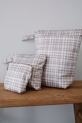 Photo shows 3 sizes of our luxe wet bags in print all plaid out. Large wet bag in print All Plaid out. Beautiful grey plaid, 2 pockets with gold zip detail. Flat bottom and handy domed handle.