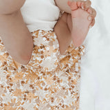 styled photo of bebe hives Reusable change mat in a happy floral print of mustards, greens, peach and rust called summer haze. Luxe quilted finish with a soft bamboo terry, machine washable, perfectly paired with modern cloth nappies, bee details on snaps.