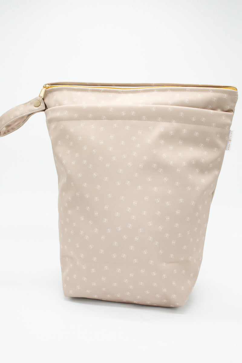 Large wet bag in print Beehave. Beautiful bronze background with a subtle bee print, 2 pockets with gold zip detail. Flat bottom and handy domed handle.