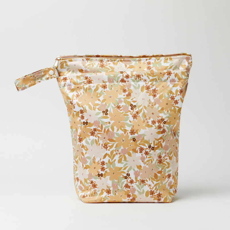 Large wet bag in print Summer Haze, floral print in a retro colour palette of mustards, peach, rust and sage., 2 pockets with gold zip detail. Flat bottom and handy domed handle